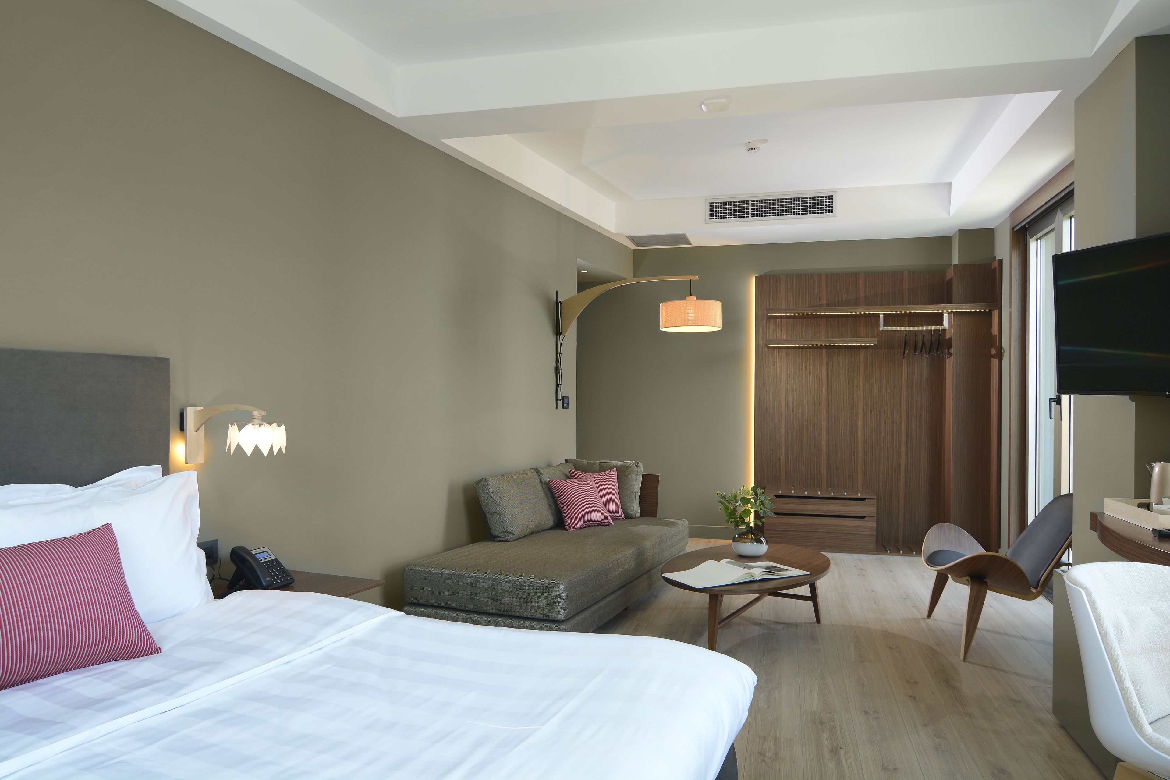 Ein Hotelzimmer mit Bett, Sofa, Couchtisch, Fernseher und Schreibtisch.