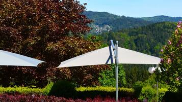 A garden with two white umbrellas, surrounded by lush greenery and flowering plants.