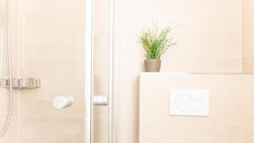 Ein Badezimmer mit Dusche, Blumentopf und Bedienfeld.
