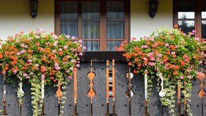 A building with a wooden fence adorned with hanging flower baskets. - Gasthof Hotel Hirschen (Kleines Wiesental)