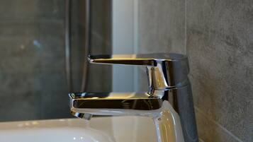 Ein modernes Badezimmer mit einem chromfarbenen Wasserhahn, einer Handbrause und einer wandmontierten Bedienkonsole.