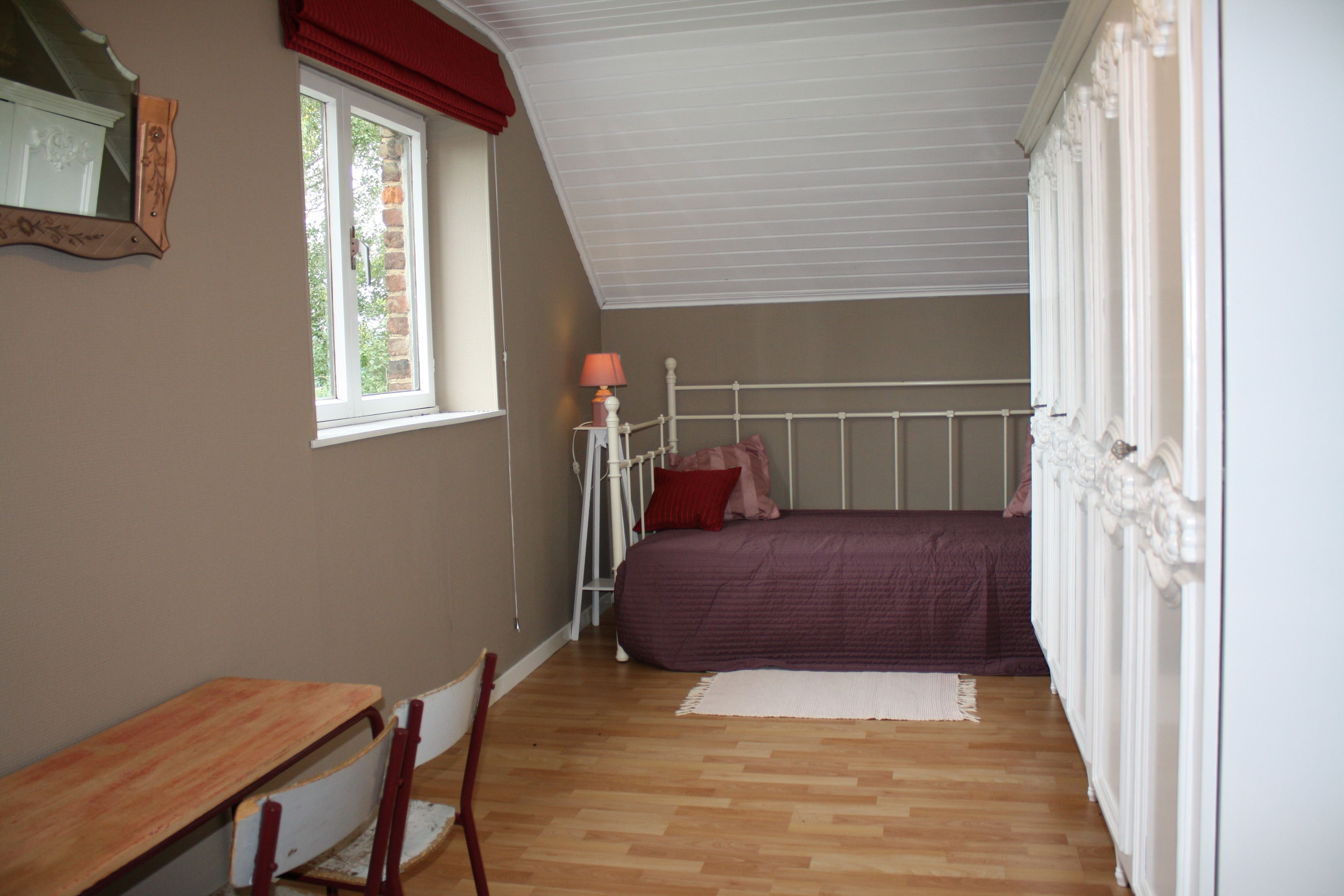 A bedroom with a bed, a desk, and a chair.