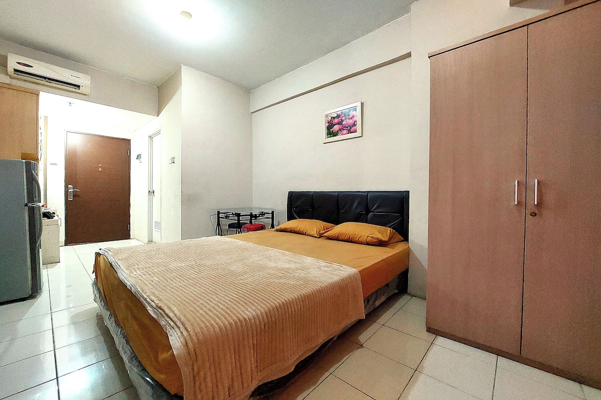 Ein Schlafzimmer mit Bett, Kleiderschrank, einem kleinen Tisch mit Stuhl und einer Klimaanlage.