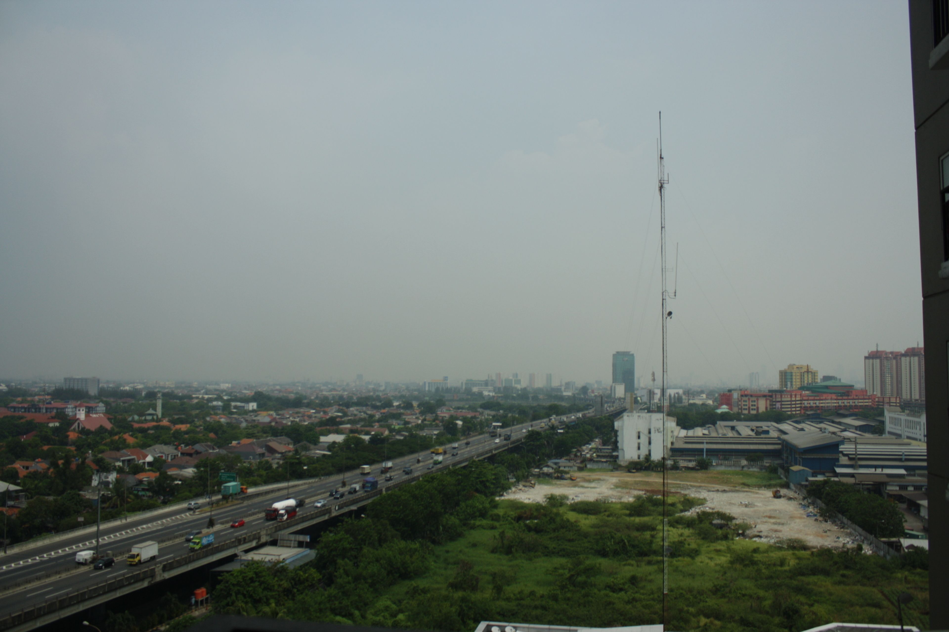 A cityscape with a highway, buildings, and a tall communication tower.