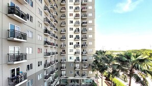A multi-story residential building with balconies, a swimming pool, and palm trees. - Adaru Property at Sunter Park View (Jakarta)