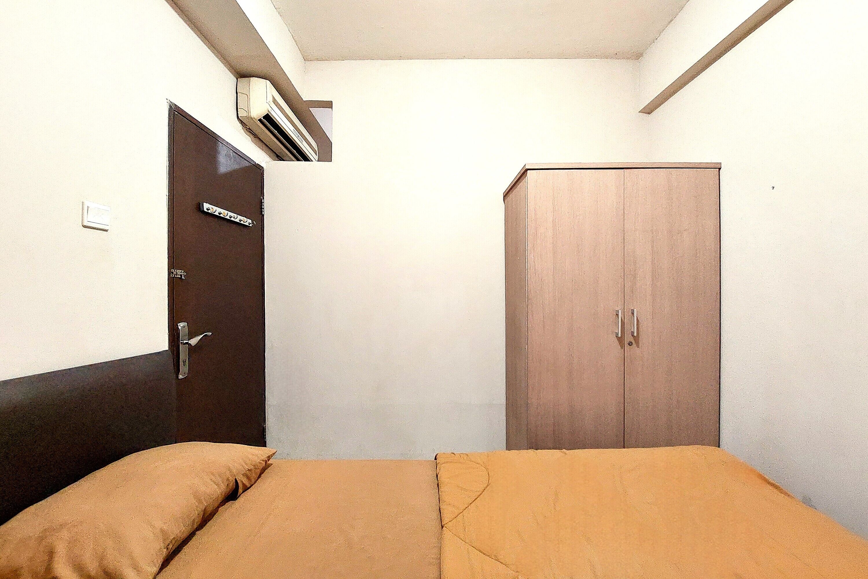 A bedroom with a bed, a wardrobe, and an air conditioning unit.