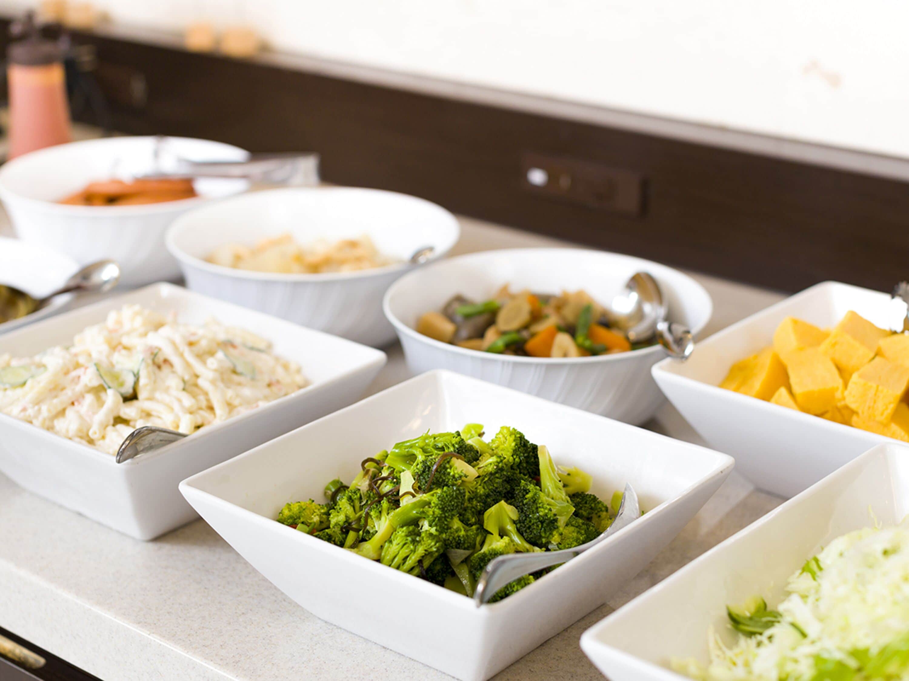 A buffet with various dishes including pasta, vegetables, and cheese.