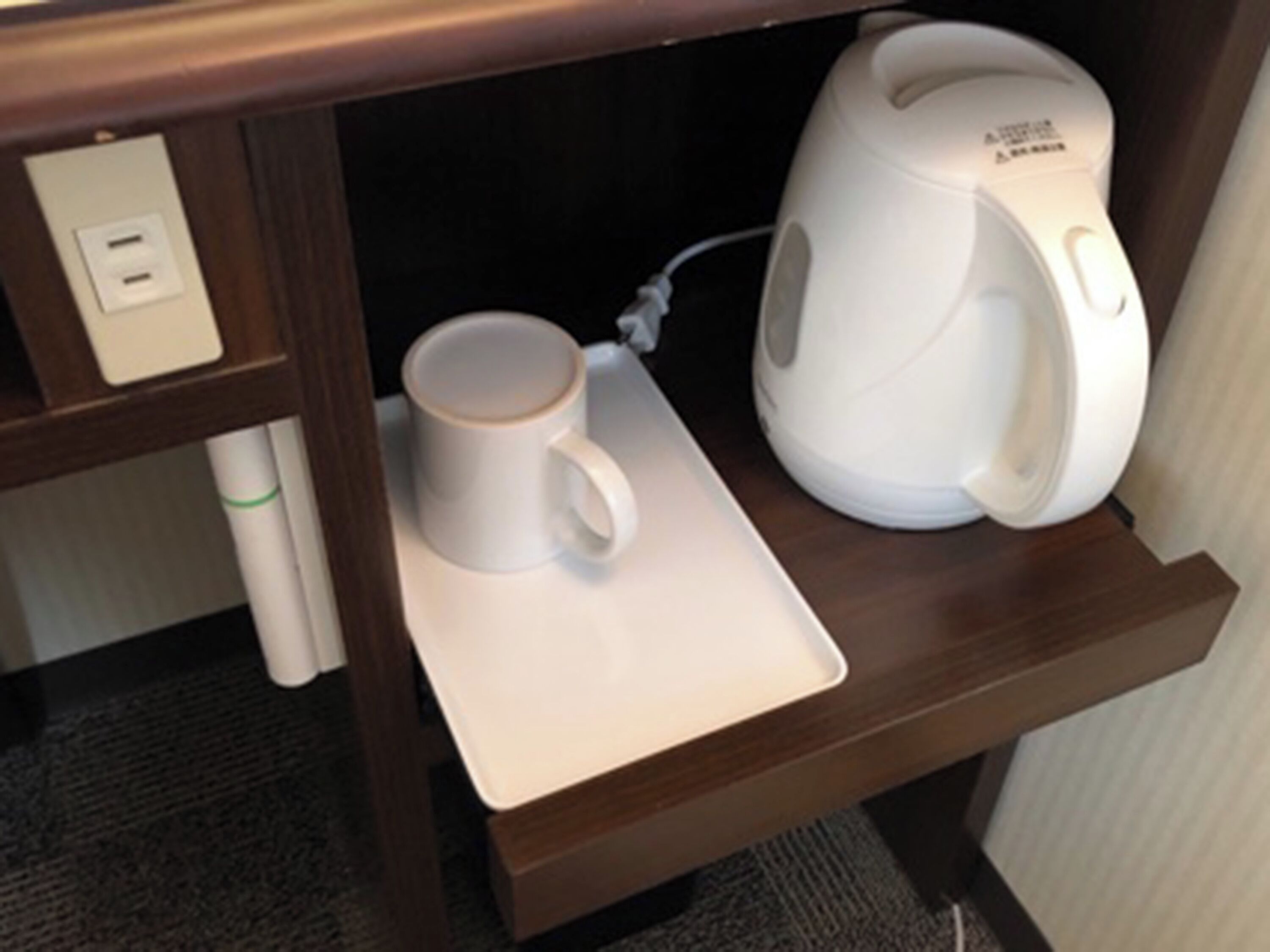 A coffee maker and a mug on a tray in a hotel room.