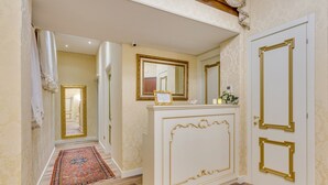 A hallway with a patterned carpet, a white door with gold trim, and a mirror with a gold frame. - Residenza Veneziana (Venice)