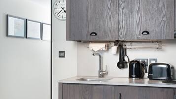 A modern kitchen with a wooden cabinet, a sink, a coffee maker, and a toaster.