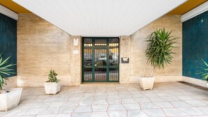 A building entrance with a tiled floor, a green door, and two potted plants. - B&B Casa Der Poeta (Rome)
