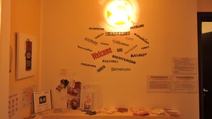A wall with a 'Welcome' sign surrounded by various languages and a light fixture. - B&B Casa Der Poeta (Rome)