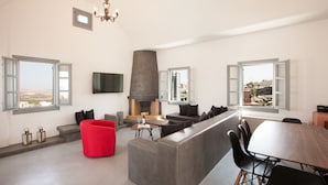 A modern living room with a fireplace, seating area, and large windows. - Adelante 88 (Santorini)