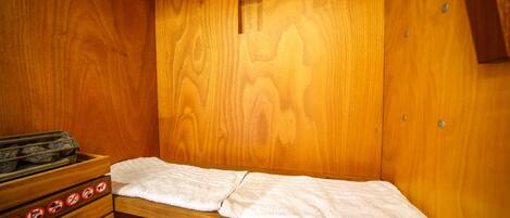 A sauna with wooden walls and benches, a towel on the bench, and a window.