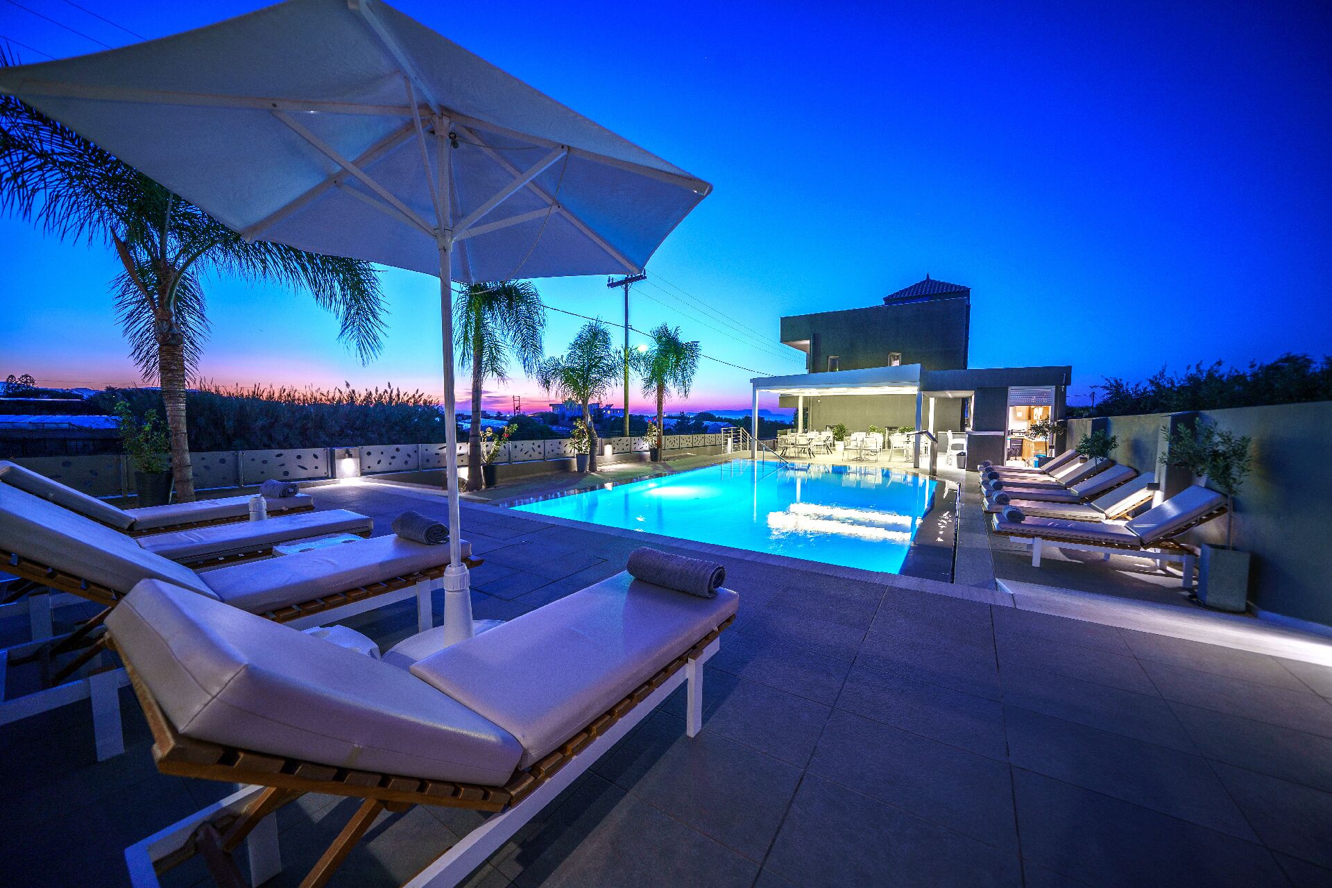 Een buitenzwembad, parasols bij het zwembad en ligstoelen