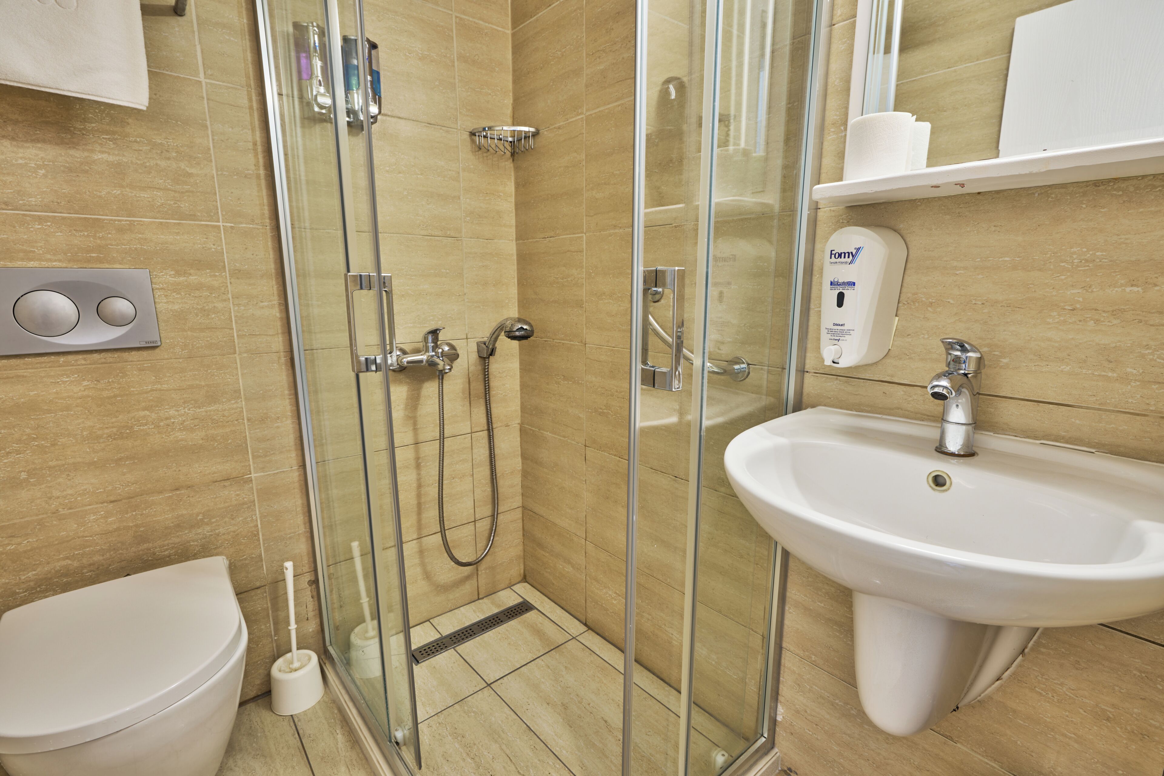 Un baño con ducha de vidrio, lavamanos blanco y retrete.