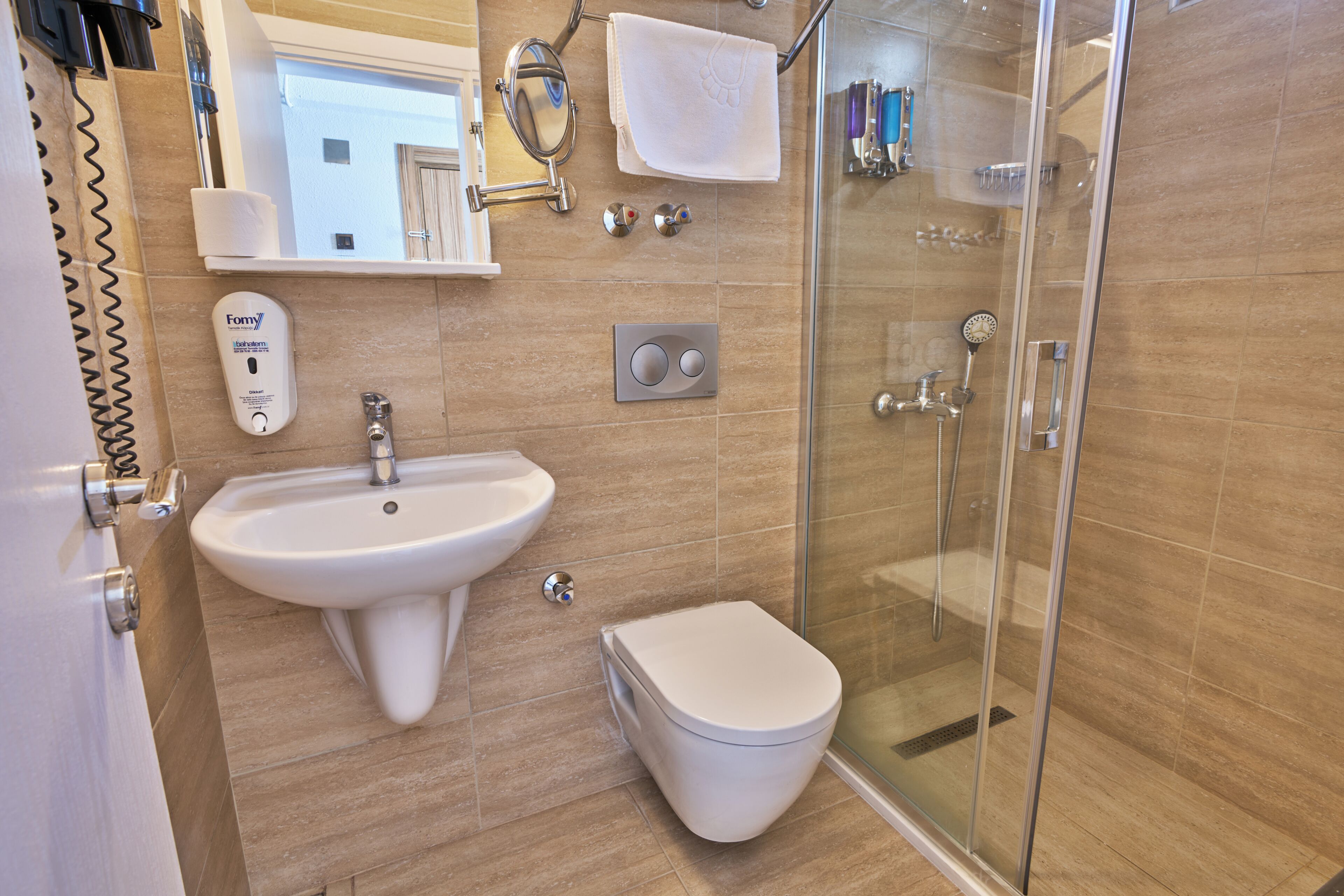 Un baño moderno con lavamanos, inodoro y cabina de ducha de vidrio.