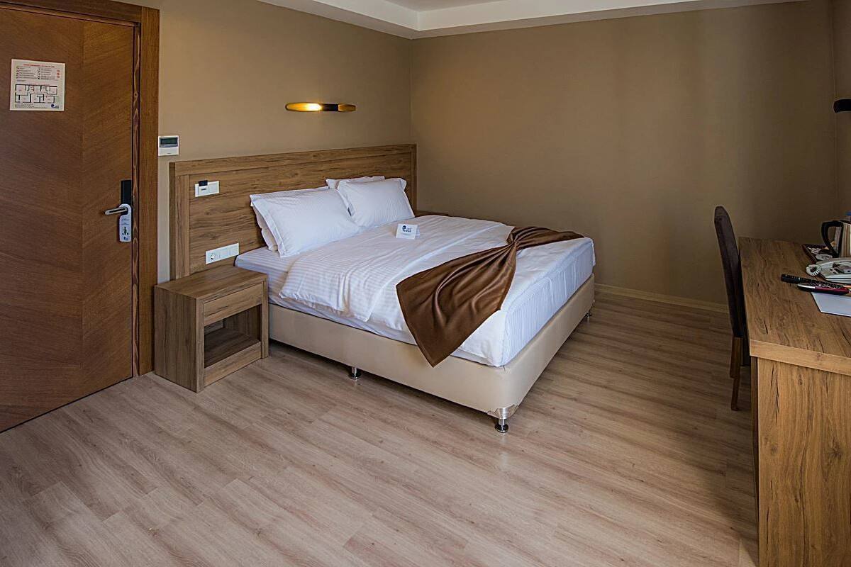 A hotel room with a bed, bedside table, desk, chair, and a flat-screen TV.