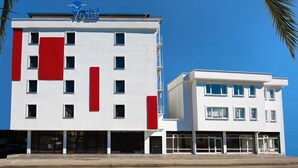 A modern hotel with a white facade and red accents, featuring multiple floors and a prominent logo at the top. - Otel Vona Ordu (Ordu)