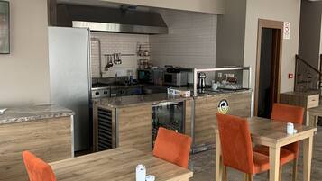 A modern kitchen with stainless steel appliances, a wooden countertop, and orange upholstered chairs.