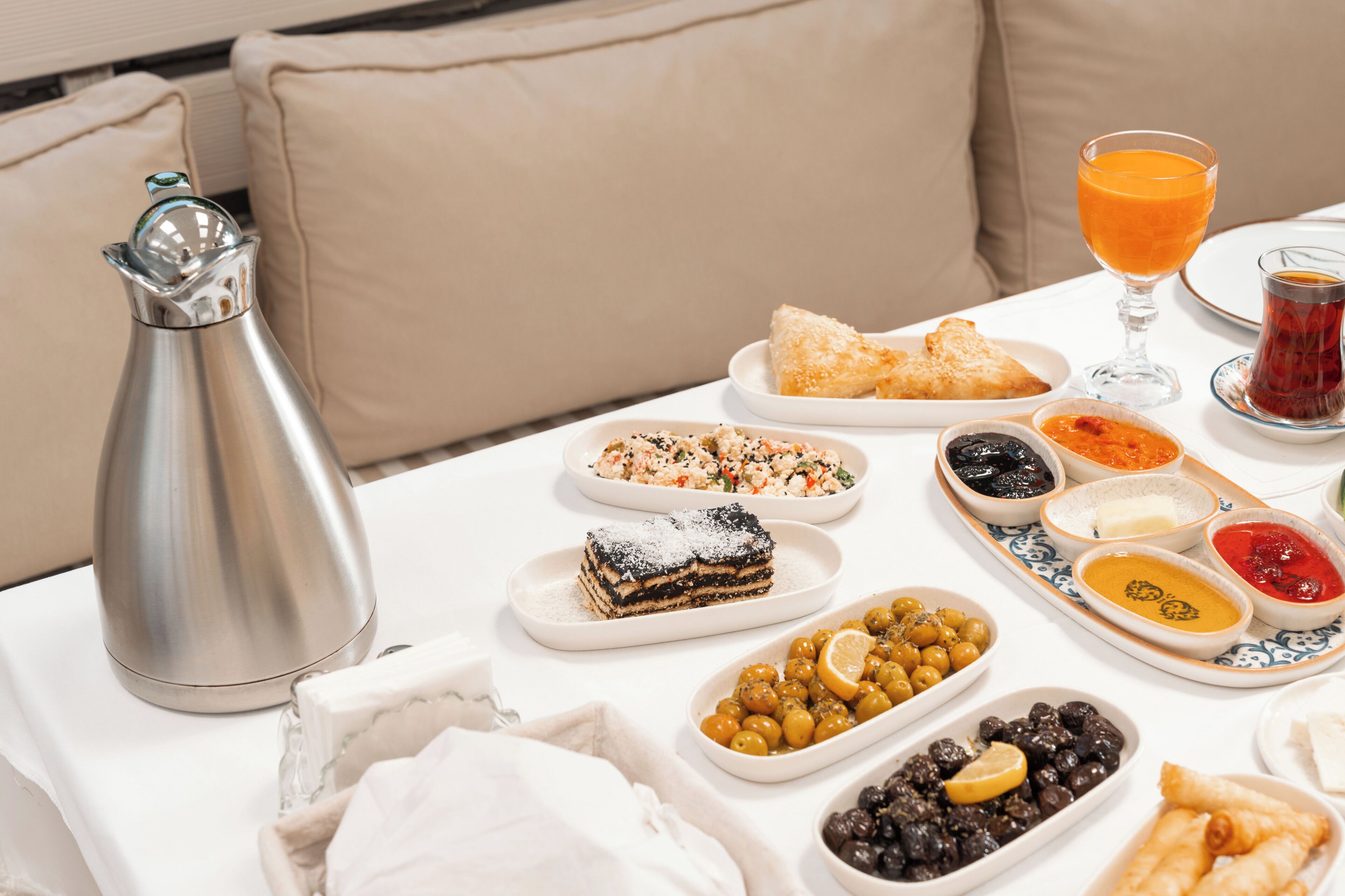 A table set with a variety of dishes, a glass of orange juice, and a glass of tea.