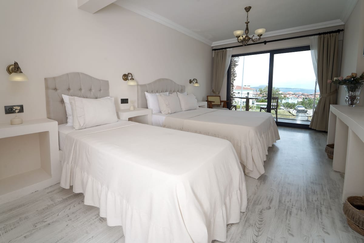Una habitación de hotel con dos camas, un balcón y una vista, además de un candelabro.