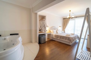 A hotel room with a bathtub, a bed with a headboard, a small refrigerator, and a window with curtains. - Cunda House Kucuk Otel (Ayvalik)