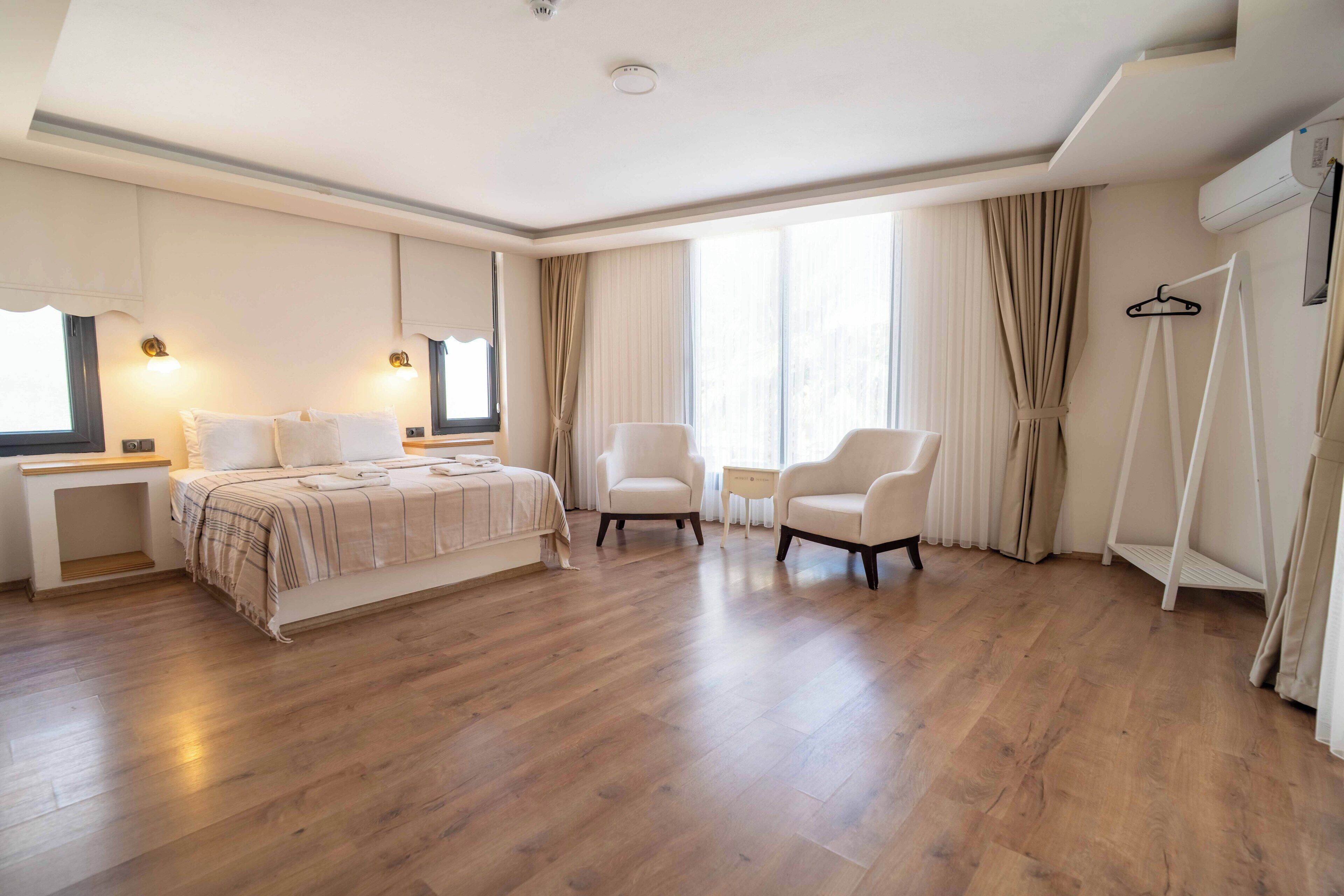 A hotel room with a bed, two chairs, a small table, and a wardrobe.