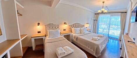 A hotel room with two beds, bedside tables, a TV, and a balcony with a view.