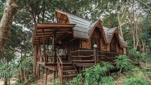 Una cabaña de madera con balcón, rodeada de un bosque frondoso.