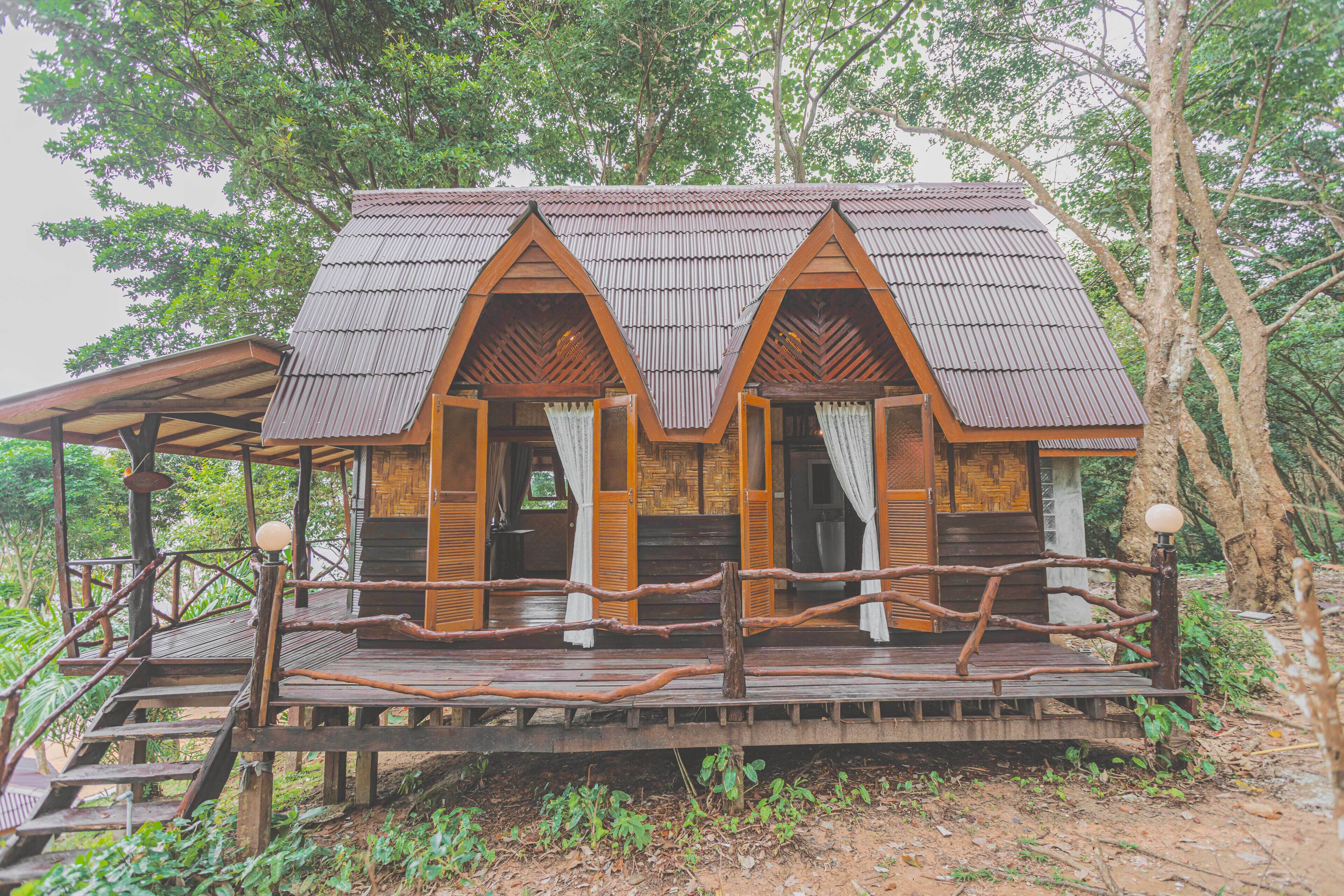 A wooden cabin with a porch, surrounded by trees.