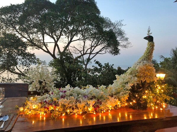 Una mesa adornada con flores blancas y luces de cuerda, rodeada de árboles y un farol.