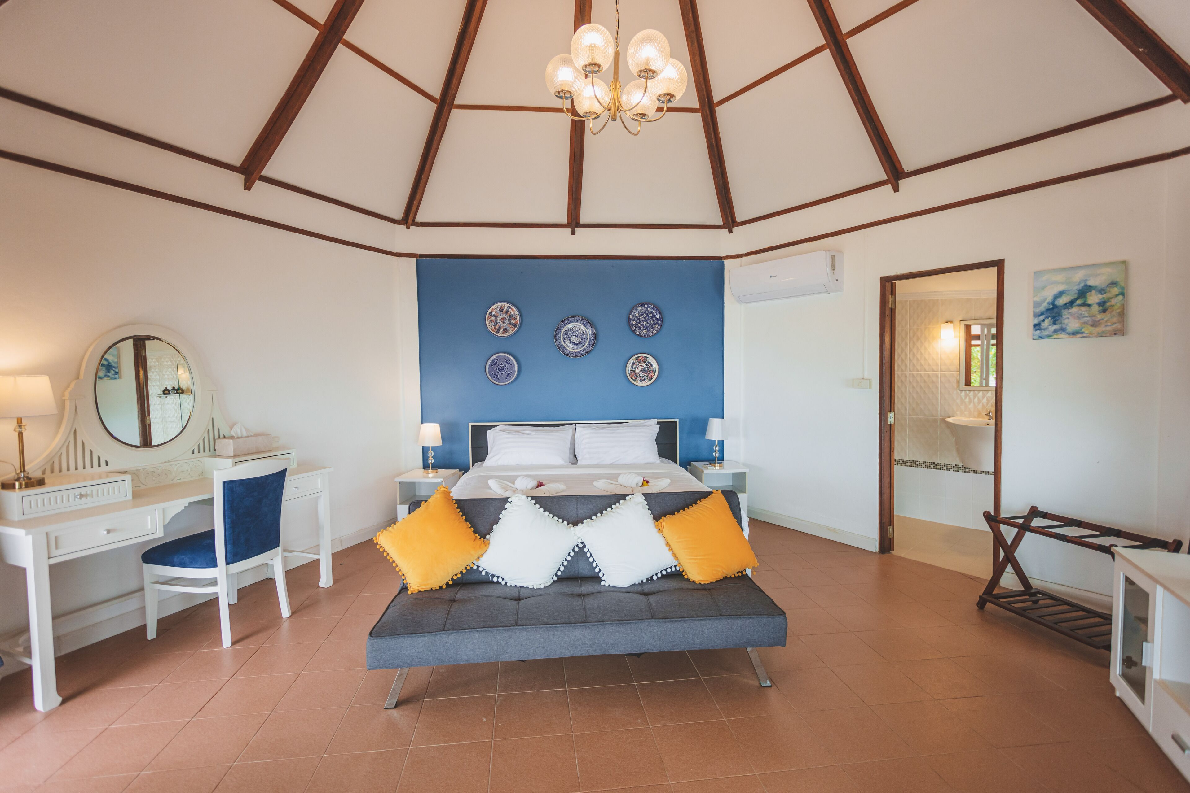 Un dormitorio con cama, mesitas de noche, escritorio, silla, espejo y candelabro.