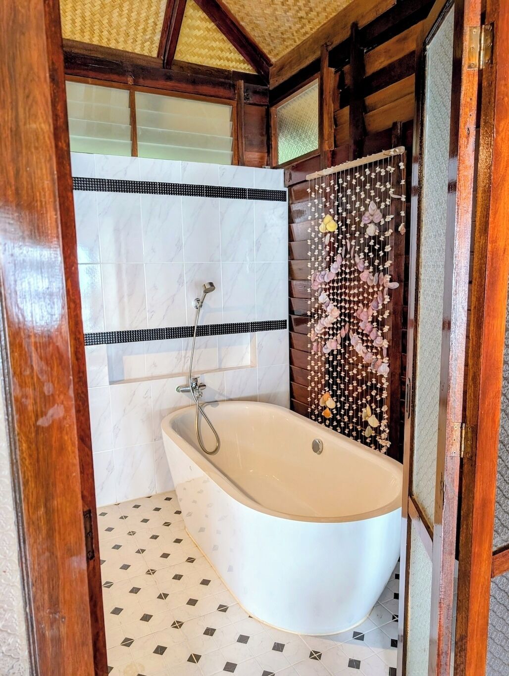 A bathroom with a freestanding bathtub, a shower, and a decorative wall.