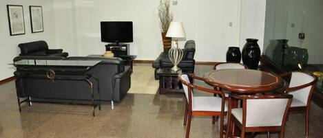 Una sala de estar moderna con un sofá, televisor, una mesa de centro y un comedor con sillas y una mesa.