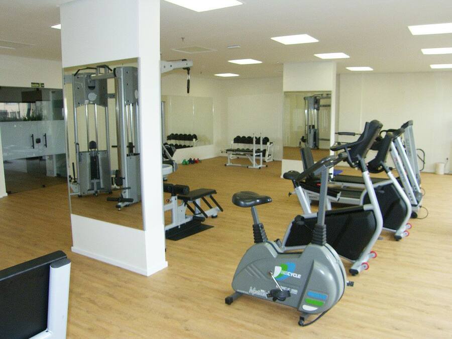 Une salle de sport équipée de matériel d’exercice, notamment des tapis de course, un vélo d’appartement et des appareils de musculation.