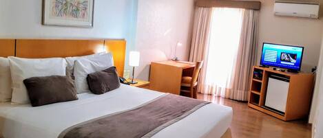 Una camera d'hotel con un letto grande, una scrivania, una televisione e un condizionatore.