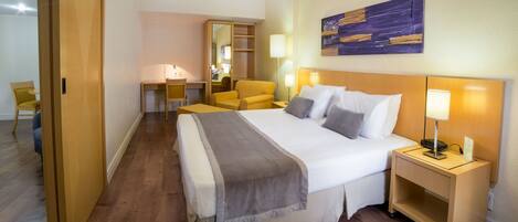 A hotel room with a large bed, bedside tables, a desk, and a chair.