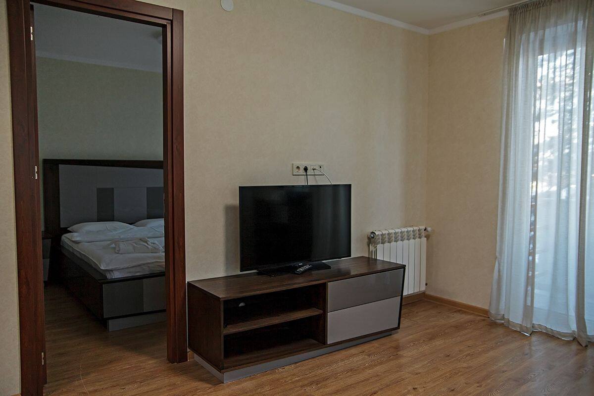 Un dormitorio moderno con una cama, un televisor sobre un mueble de madera y un radiador.