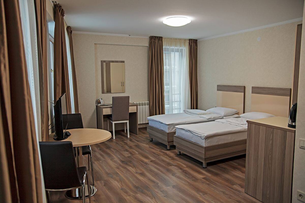 Habitación de hotel con dos camas, un escritorio, una silla y una mesita.