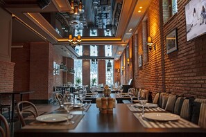 A restaurant with brick walls, wooden tables, and modern lighting fixtures. - Orbi Palace Hotel & Suites (Borjomi)