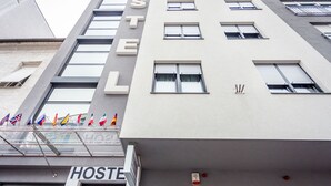 Un bâtiment abritant une auberge de jeunesse, avec de nombreuses fenêtres et une enseigne indiquant « AUBERGE ». Des drapeaux sont accrochés au balcon.