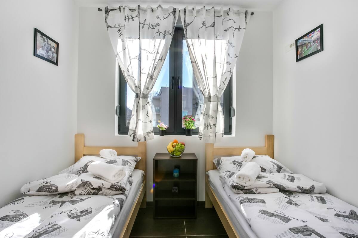 A twin room with two beds, a nightstand, and a window with curtains.