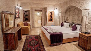 Un dormitorio con una cama grande, un aparador de madera, un sofá y una alfombra estampada.