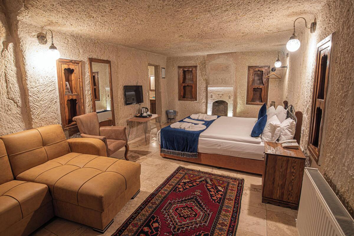 A cozy room with a large bed, a sofa, a small table, and a television.