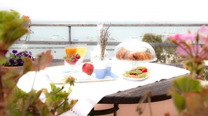 A table set with a breakfast spread including croissants, a fruit salad, and juice, overlooking a marina. - La dolce vista (Manfredonia)