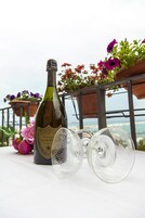 Una botella de vino y dos copas de vino vacías sobre una mesa con vista al mar.