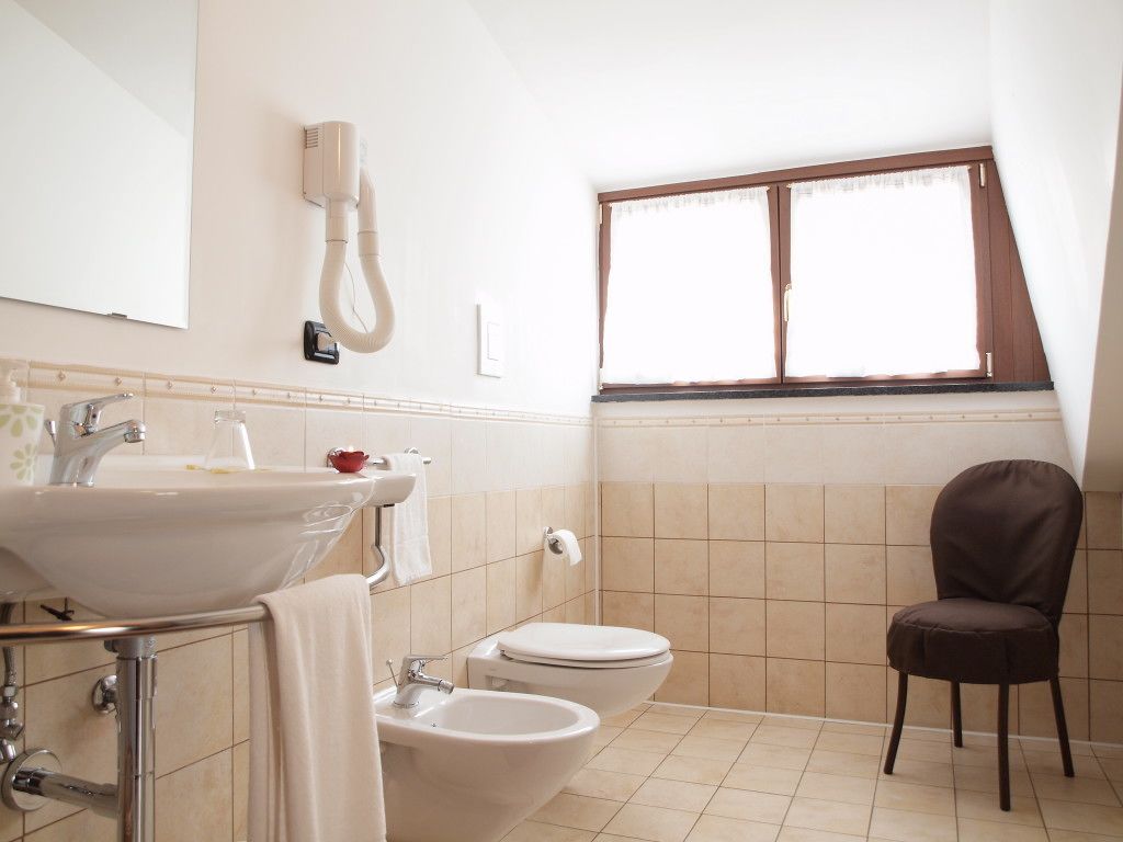 Un baño con lavamanos, bidé, inodoro y una silla.
