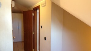 A hallway with a wooden door, a white wall, and a tiled floor.