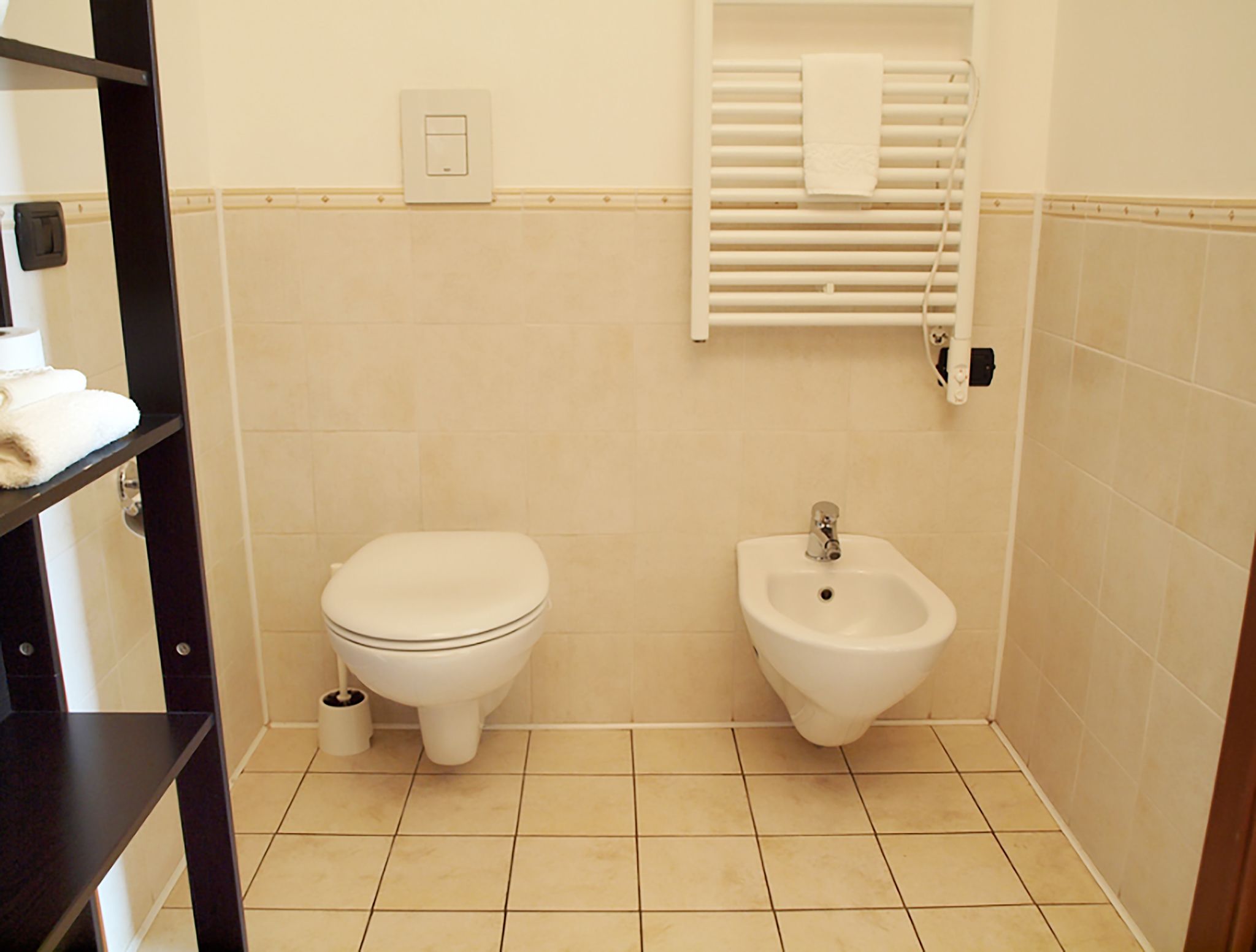 Un baño pequeño con inodoro, bidé y toallero.